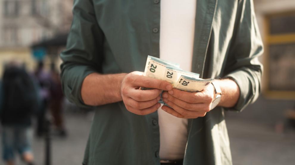 Close-up view of young man holding and counting euro bills