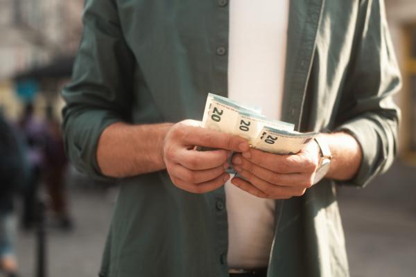 Close-up view of young man holding and counting euro bills